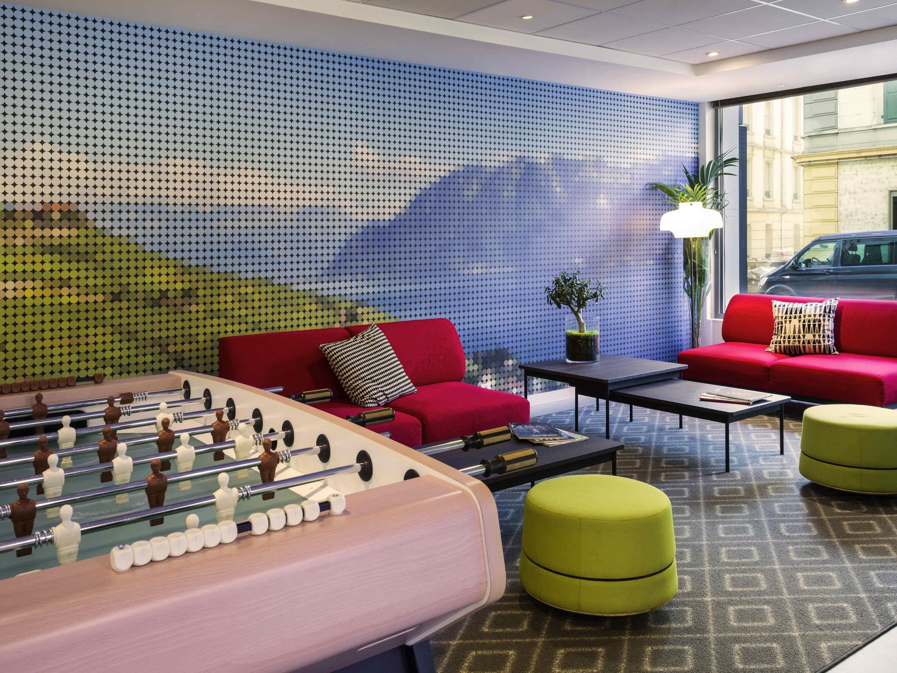 Un'area lounge moderna con tavolo da calcio, divani rossi e parete decorata.