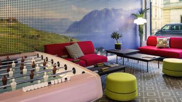 Un'area lounge moderna con tavolo da calcio, divani rossi e parete decorata.
