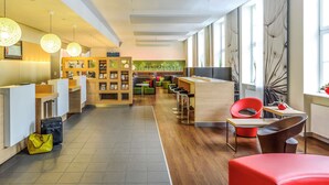 A modern hotel lobby with a reception desk, seating areas, and large windows. - ibis Karlsruhe Hauptbahnhof (Karlsruhe)