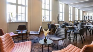 A modern interior with multiple seating areas, large windows, and a wall decorated with vinyl records. - ibis Karlsruhe Hauptbahnhof (Karlsruhe)