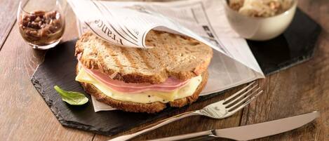 A sandwich on a slate board with a fork and knife beside it.