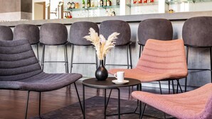A bar area with multiple seating options, including chairs and a table with a vase and a cup. - ibis Karlsruhe Hauptbahnhof (Karlsruhe)