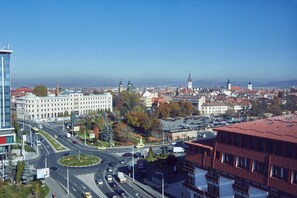 A cityscape with a prominent roundabout, various buildings including a large white structure with a green dome, and a red-roofed building with a grid-like facade. - MyContinental Sibiu (Sibiu)