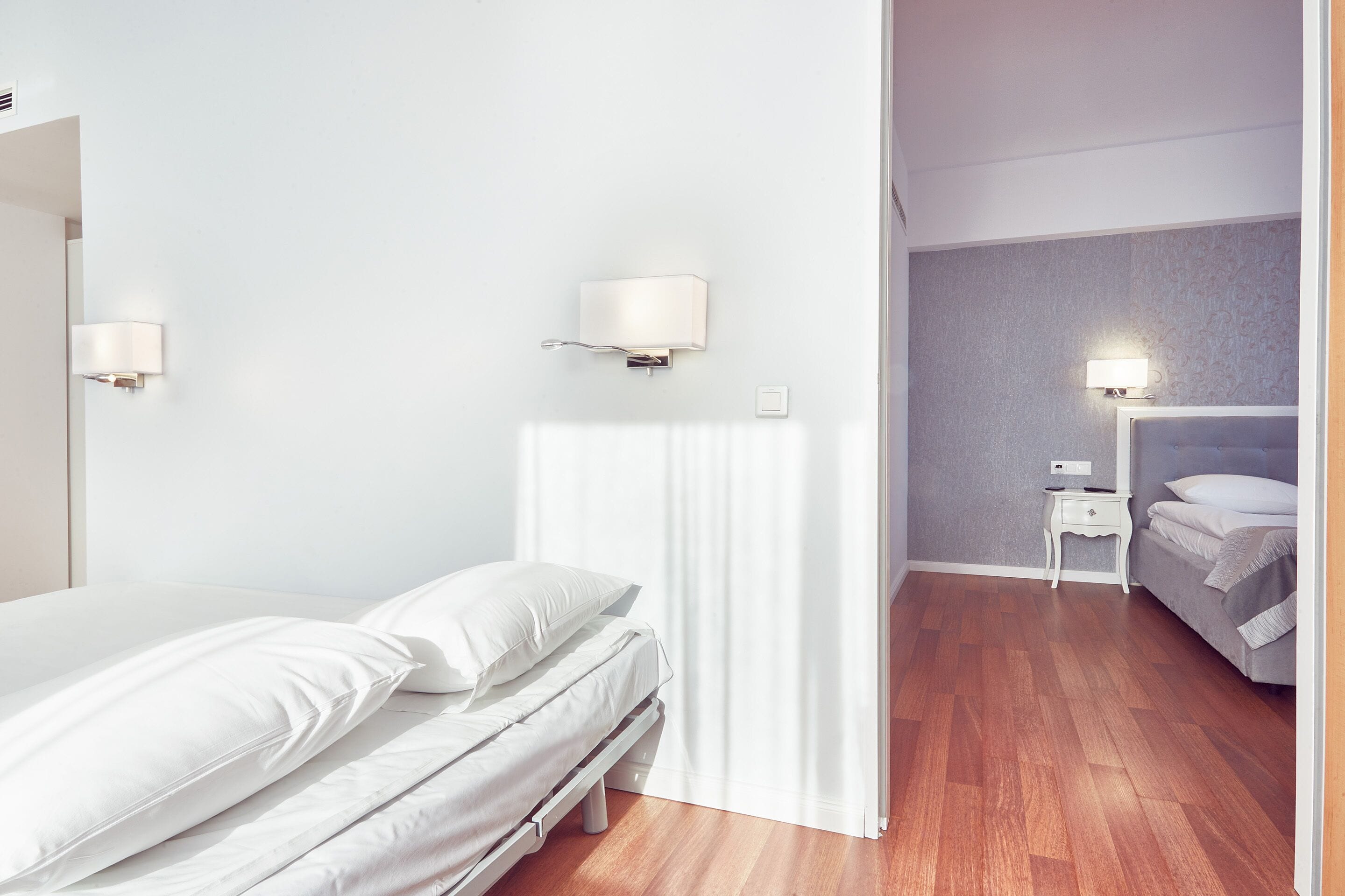 A bedroom with a bed, two bedside tables, a nightstand, and a curtain.