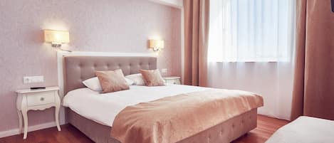 Un dormitorio ordenado con una cama grande, mesitas de noche y una ventana con cortinas.