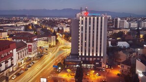 Vista urbana con un edificio destacado que muestra el rótulo 'Continental', rodeado de otros edificios y una calle concurrida con estelas de luz que sugieren movimiento.