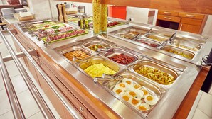 Un bufé con diversas opciones de comida, como huevos, salchichas y papas.