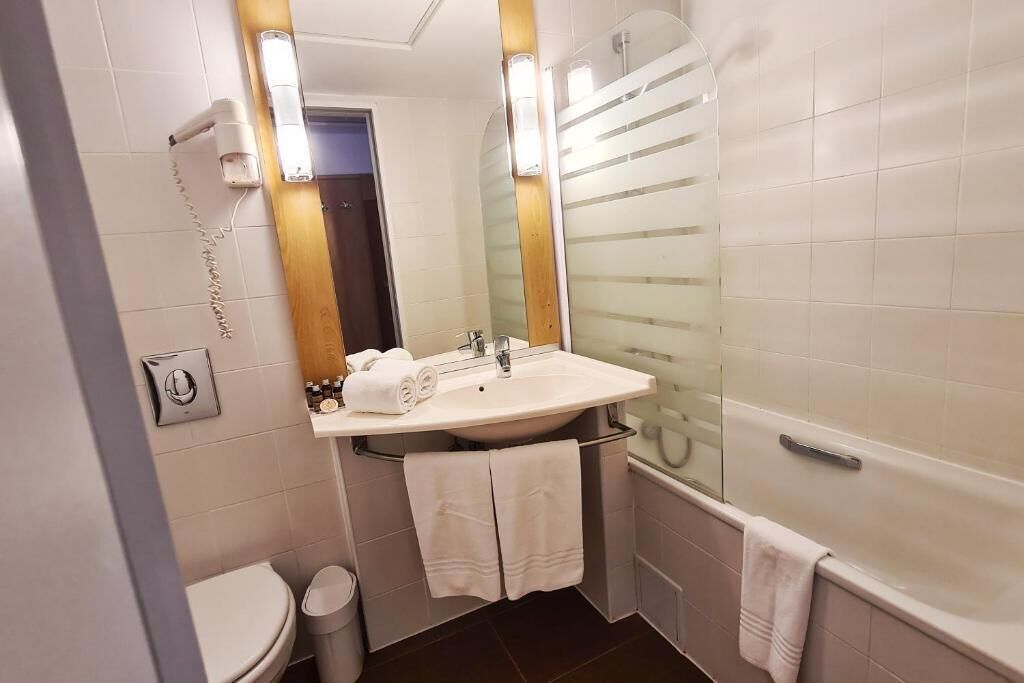Un baño con inodoro, lavabo y bañera. Hay toallas colgadas en la pared y una cortina de ducha.