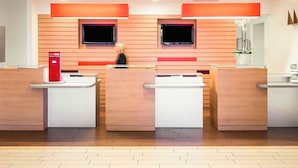 Een receptie met drie balies, houten paneelwanden en twee monitoren.