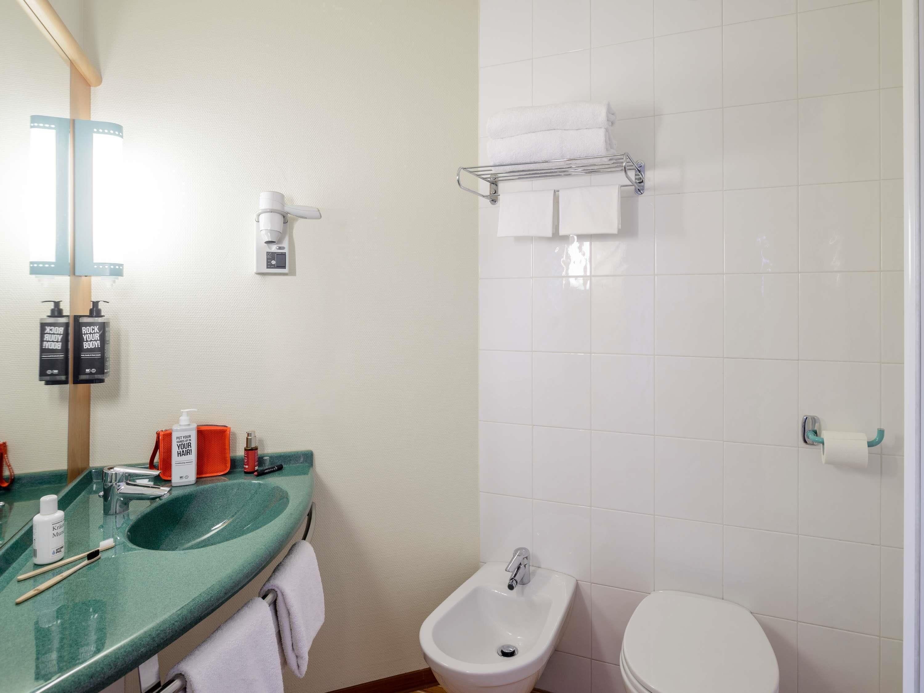 Un baño con un lavamanos verde, un bidé, un inodoro y un perchero para toallas.