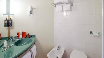Un baño con un lavamanos verde, un bidé, un inodoro y un perchero para toallas.