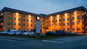 Een meerlaags hotel met een parkeerplaats ervoor.
