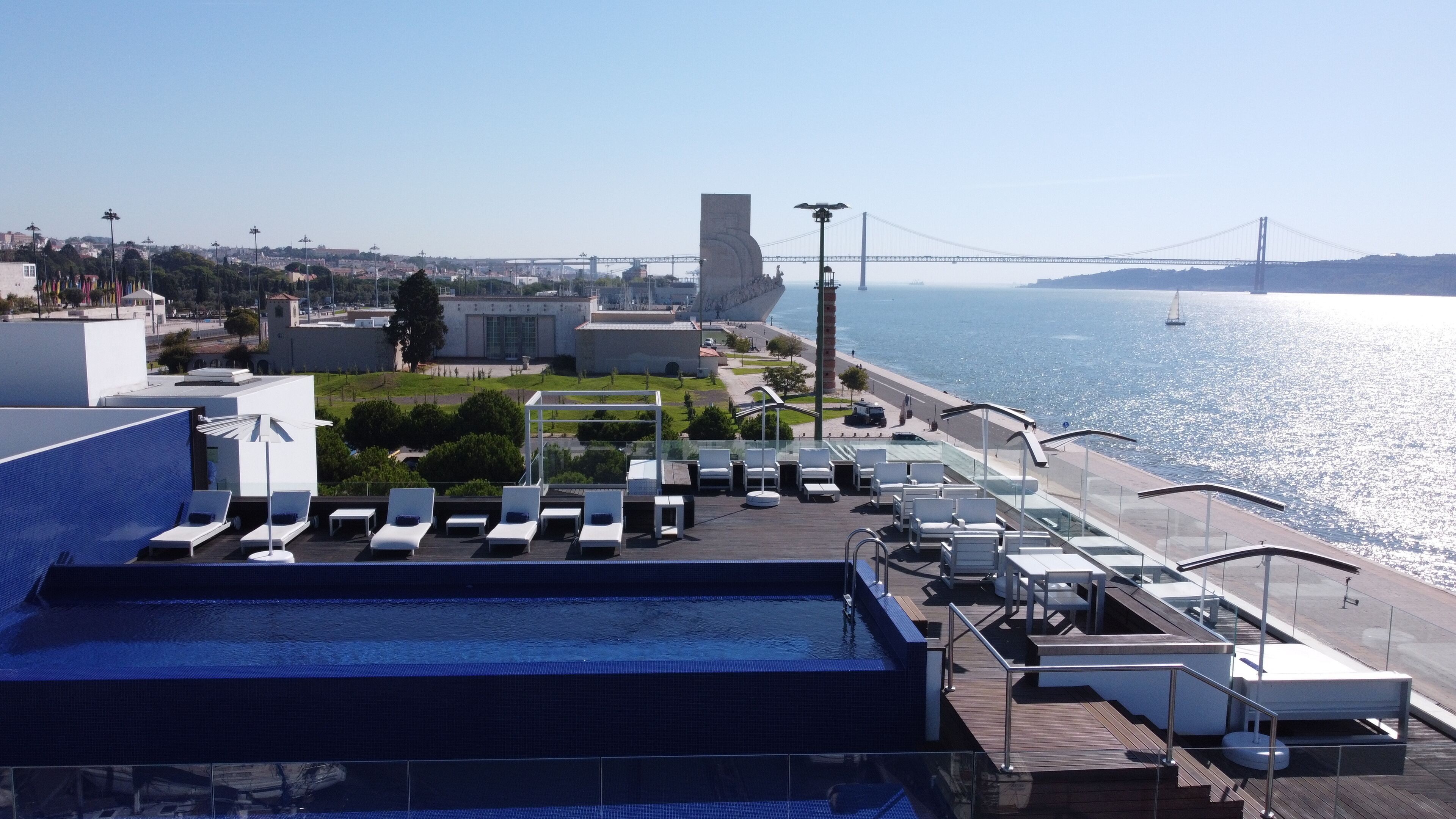 Un espace piscine aménagé sur le toit, avec des chaises longues et une vue sur la ville et un pont.