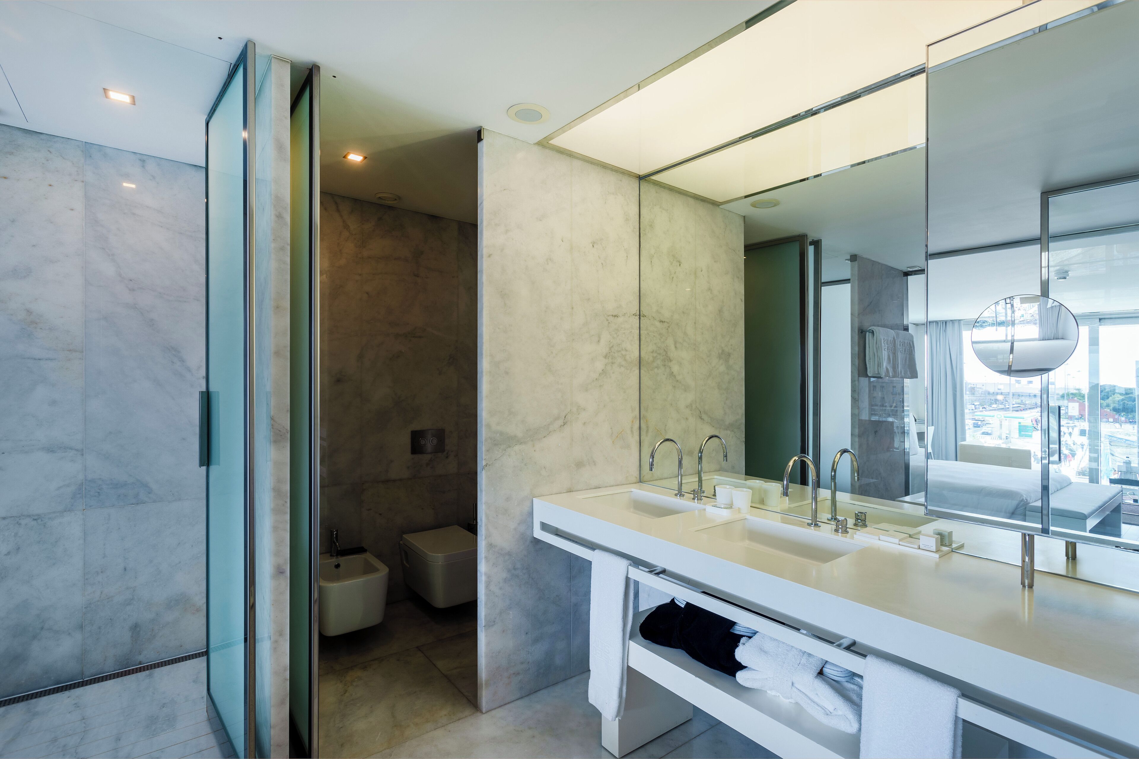 A modern bathroom with a large mirror, dual sinks, and a walk-in shower.