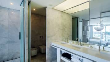 A modern bathroom with a large mirror, dual sinks, and a walk-in shower.