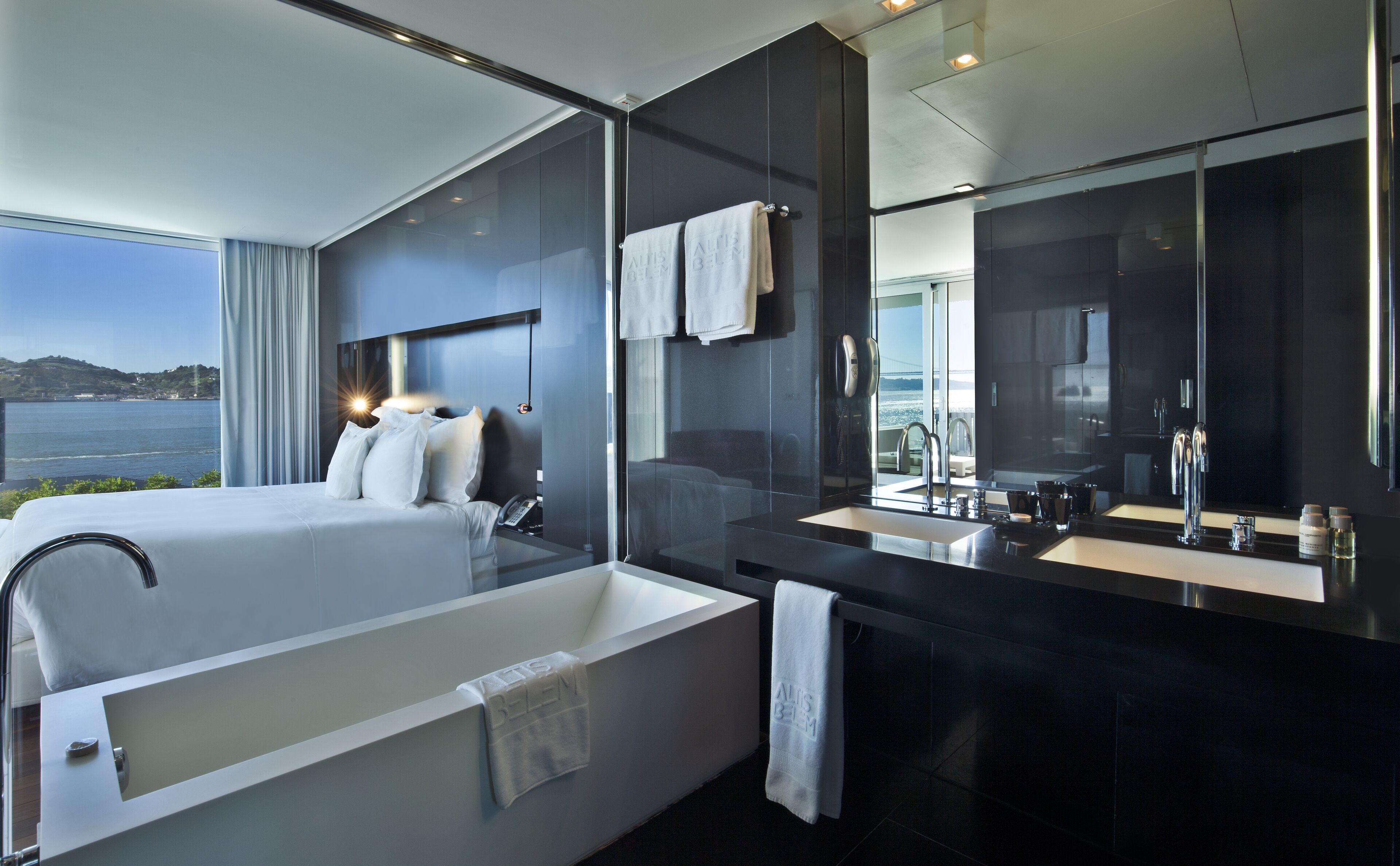 Quarto de hotel moderno com uma banheira grande, área de chuveiro separada e toucador com um espelho amplo.