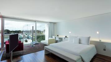 Une chambre d’hôtel moderne avec un grand lit, un bureau et une vue sur le paysage urbain.