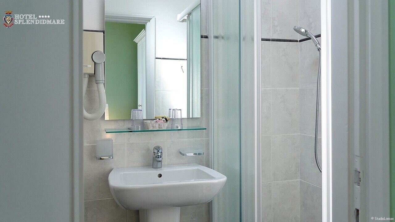 Un baño moderno con cabina de ducha de vidrio, un lavabo blanco y un espejo.
