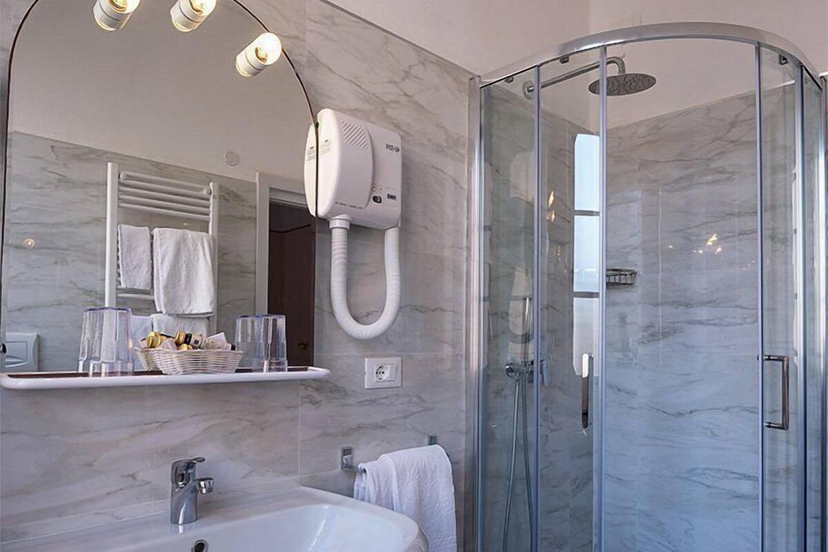 A modern bathroom with a large mirror, a sink, a glass-enclosed shower, and a towel rack.