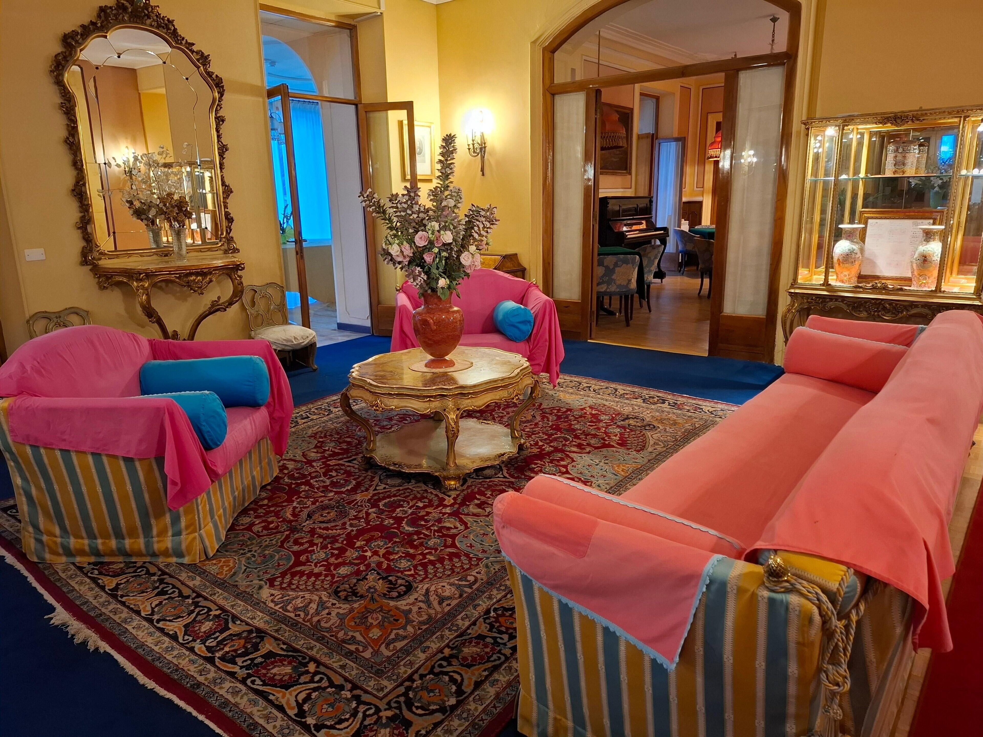 Una habitación con alfombra estampada, una mesa redonda con un jarrón y dos sofás tapizados con rayas.