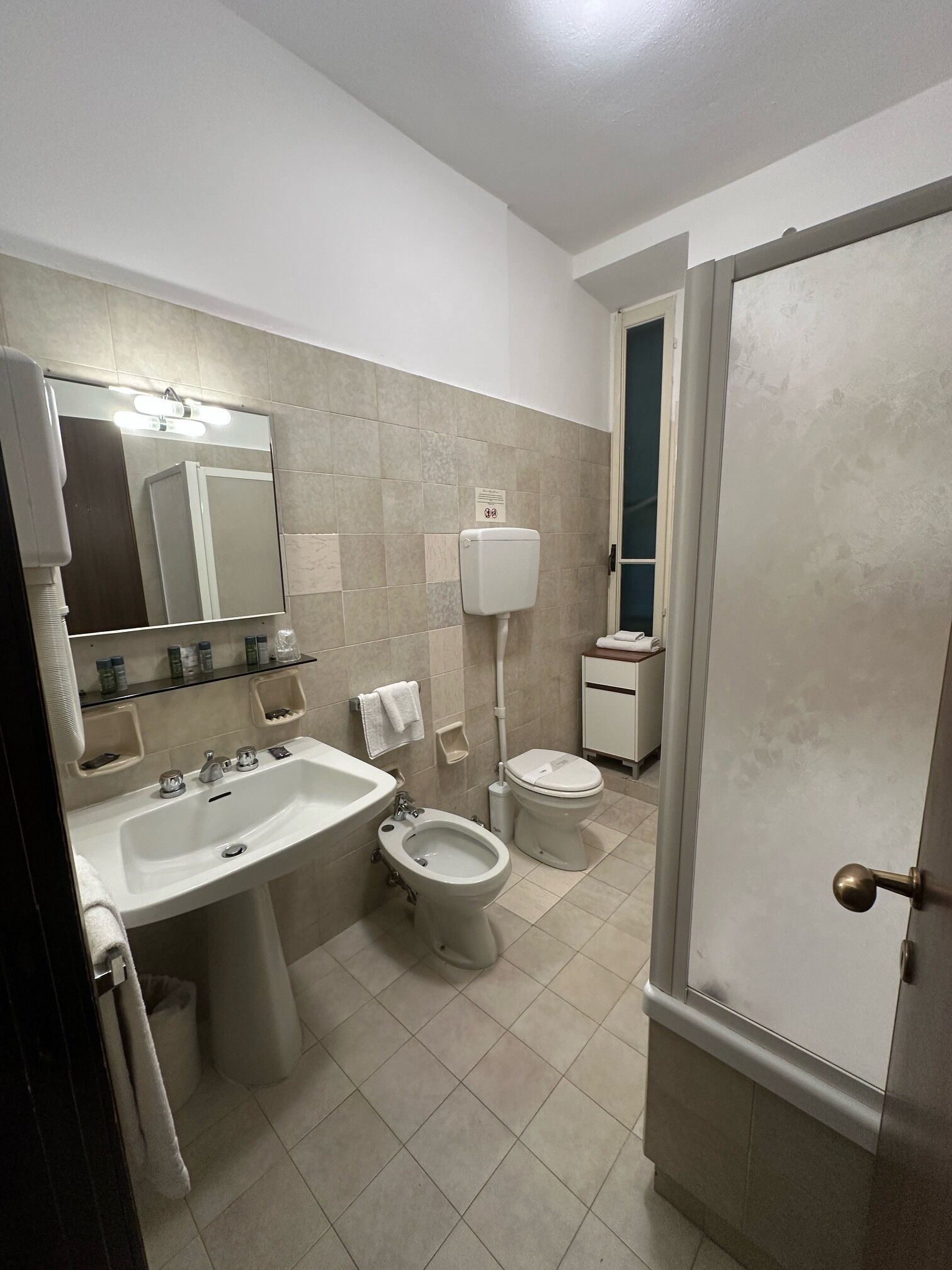 A bathroom with a sink, bidet, toilet, and a mirror.