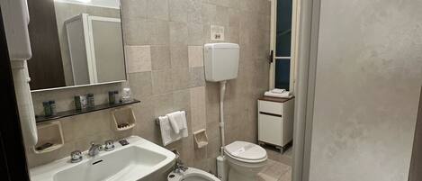 A bathroom with a sink, bidet, toilet, and a mirror.