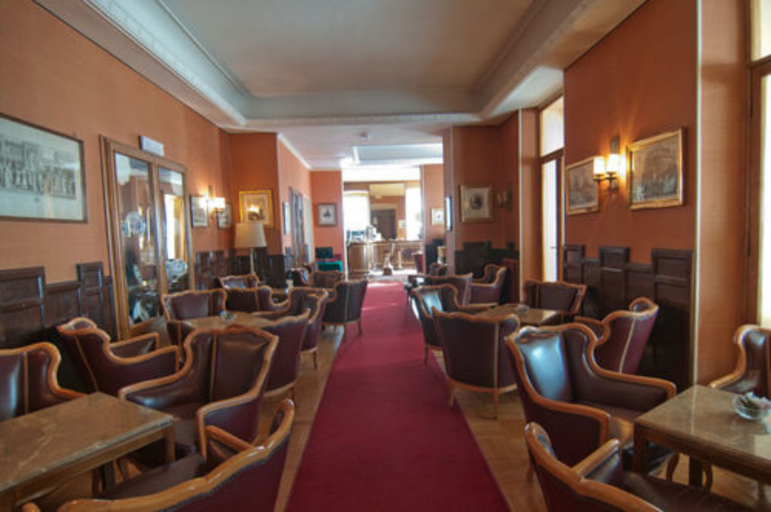 Un vestíbulo de hotel con alfombra roja, muebles de madera y cuadros en las paredes.