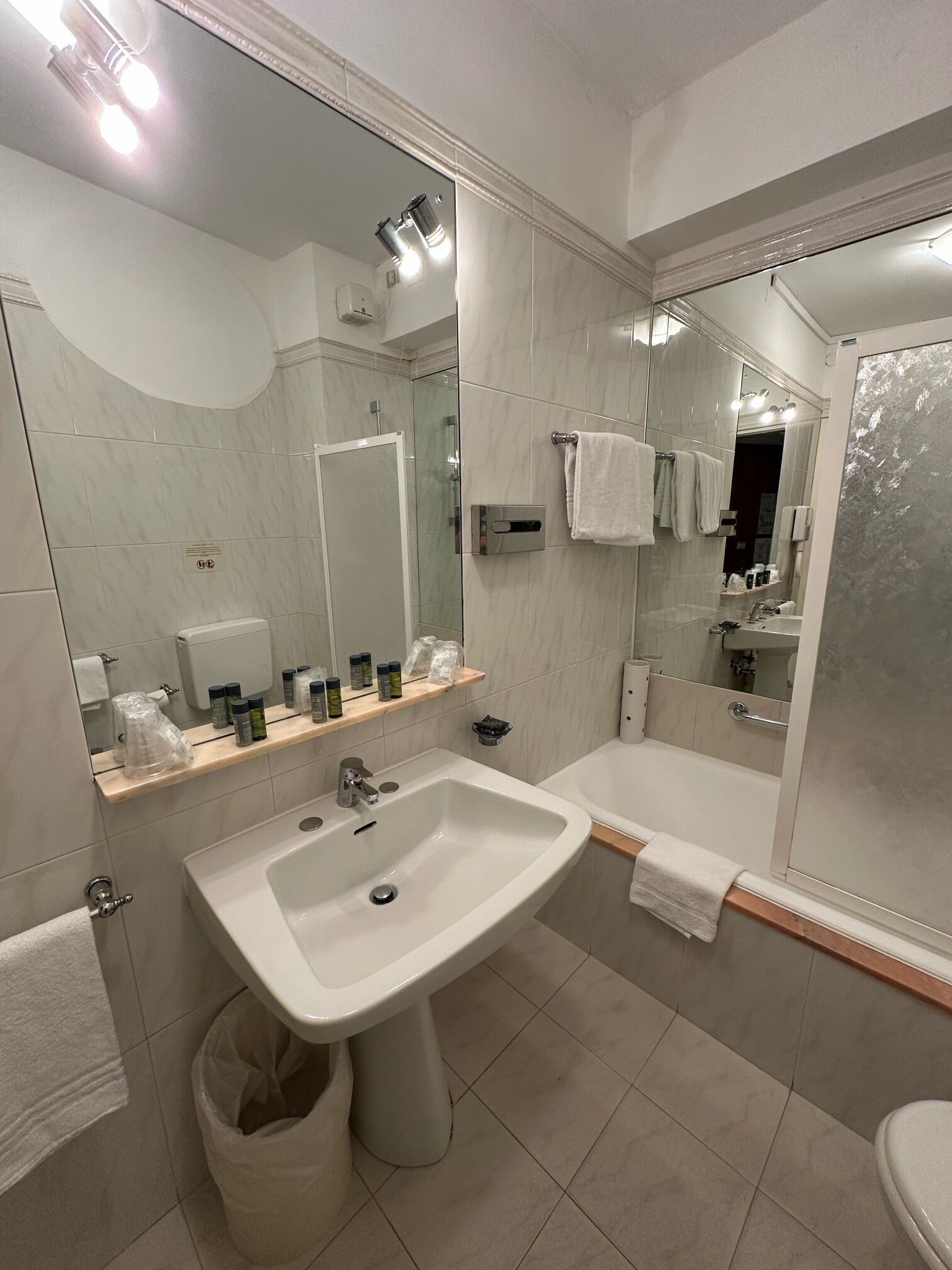A modern bathroom with a large mirror, a sink, a bathtub, and a shower.