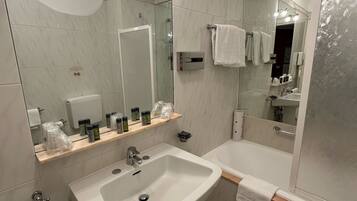 A modern bathroom with a large mirror, a sink, a bathtub, and a shower.