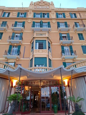La façade d’un hôtel, ornée de balcons, et une enseigne indiquant « LONDRA GRAND HOTEL ».