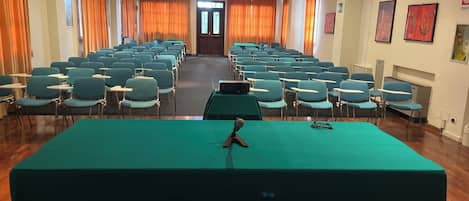 A conference room with rows of chairs, a long table, and a door at the end.