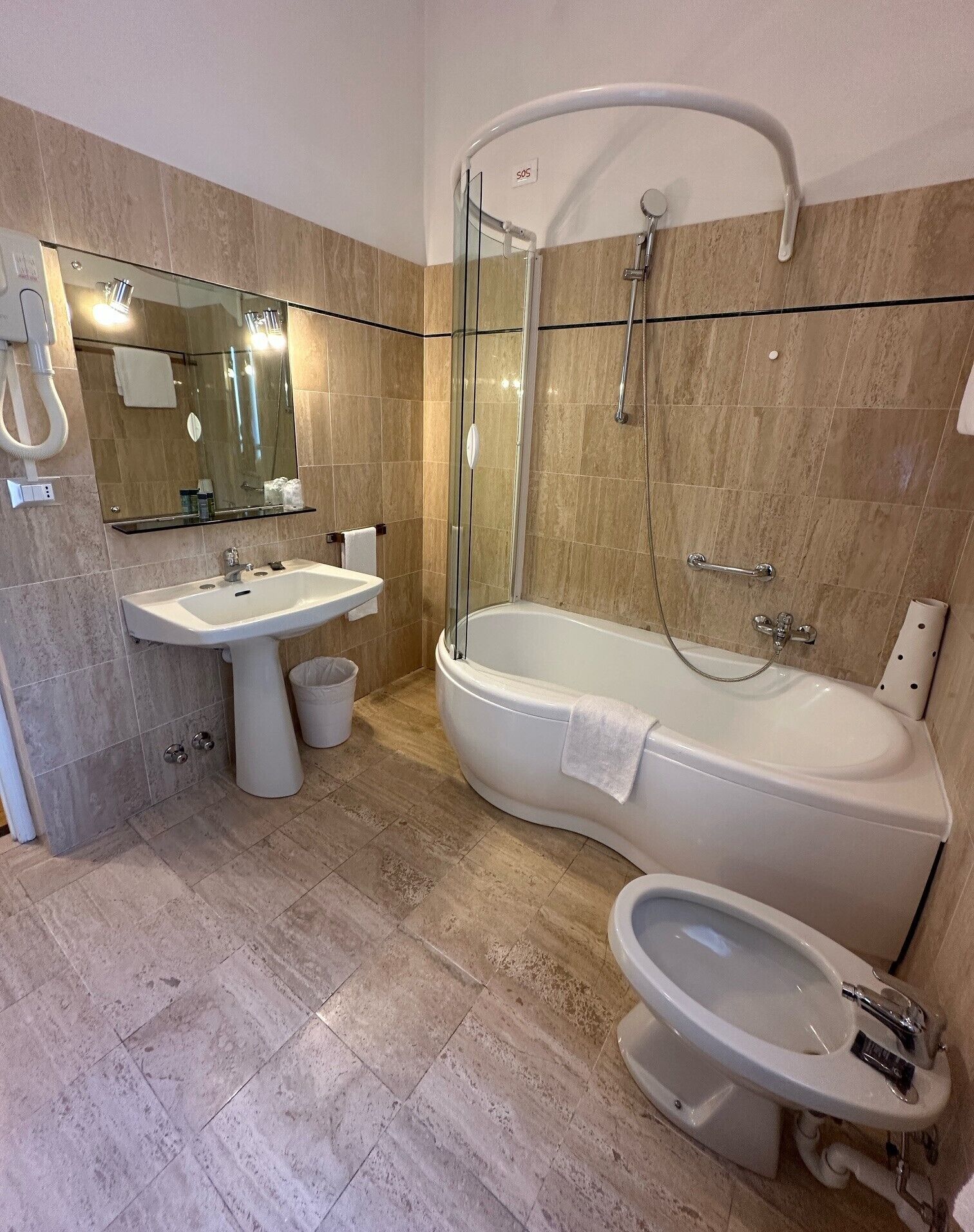 Un baño moderno con ducha envuelta en vidrio, una bañera independiente, un lavabo pedestal y un inodoro.