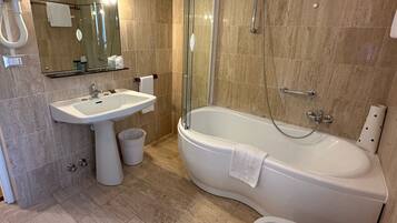 Un baño moderno con ducha envuelta en vidrio, una bañera independiente, un lavabo pedestal y un inodoro.