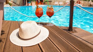 Una terraza de madera con un sombrero de paja y dos bebidas con pajitas.