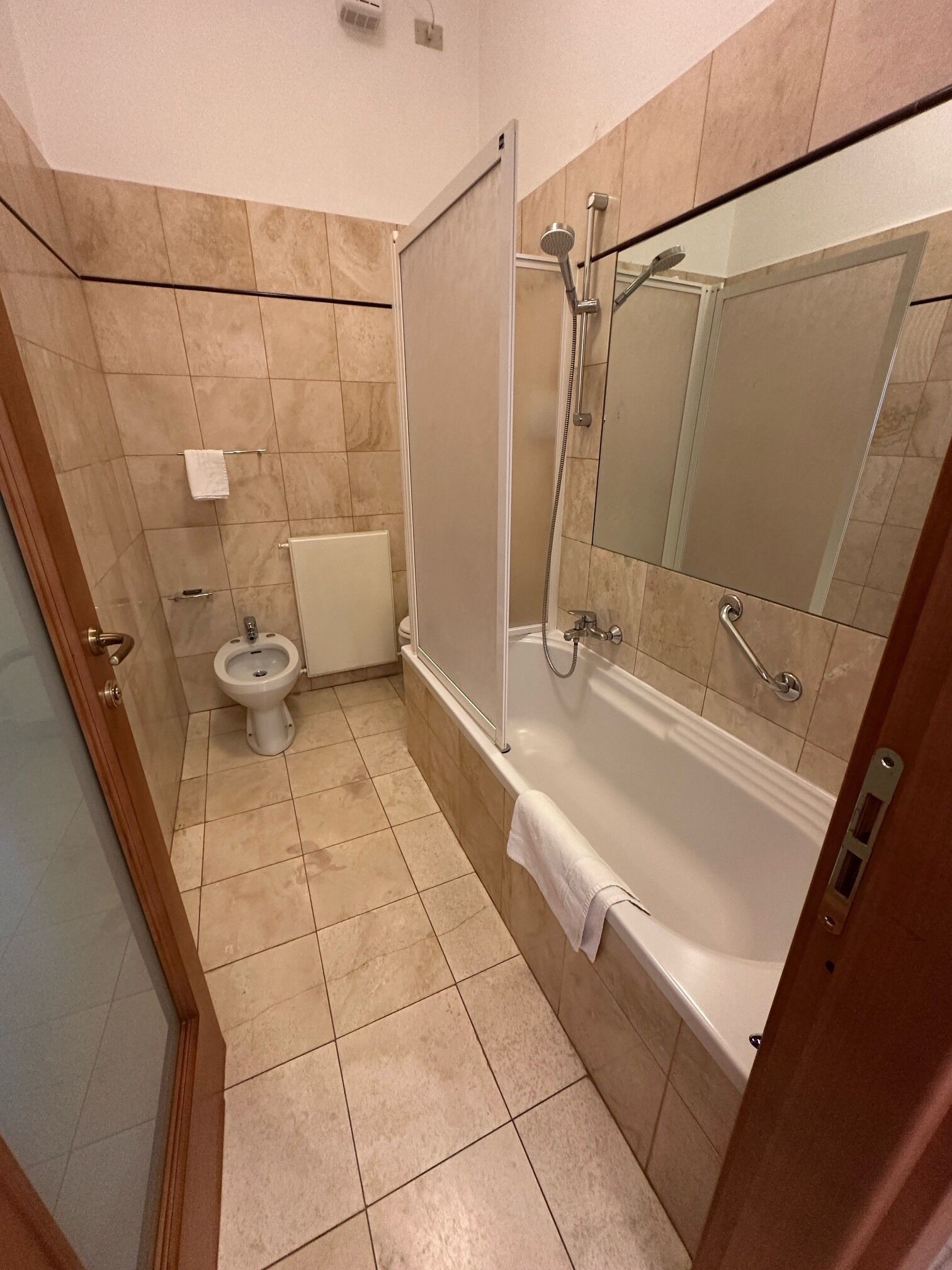 A bathroom with a toilet, a shower, a bathtub, and a mirror.