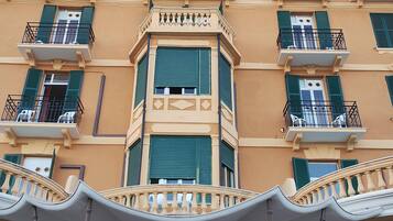 Un hotel a più piani con balconi, un ingresso centrale e un cartello con scritto 'LONDRA GRAND HOTEL'.