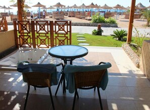A patio area with a hot tub, two wicker chairs, and a view of the beach. - Imperial Shams Abu Soma (Safaga)