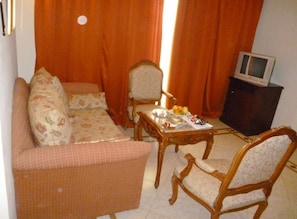 A living room with a sofa, two armchairs, a coffee table, and a television on a cabinet. - Imperial Shams Abu Soma (Safaga)