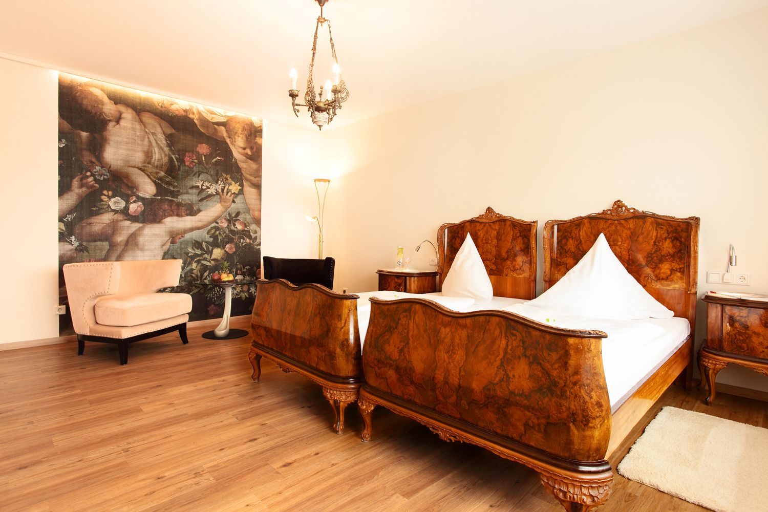 Un dormitorio con una cama grande, una silla, una mesita de noche, una lámpara y un cuadro en la pared.