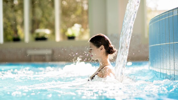 A person in a swimming pool with water flowing from the side. - Hotel Wulff (Bad Sassendorf)