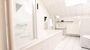 Un baño moderno con ducha de vidrio, bañera y retrete.
