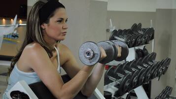 Una persona ejercitando con mancuernas en un gimnasio.