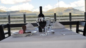 A table set with a bottle of wine, two wine glasses, a dessert, and cutlery. - Epic Hotel San Luis (La Punta)