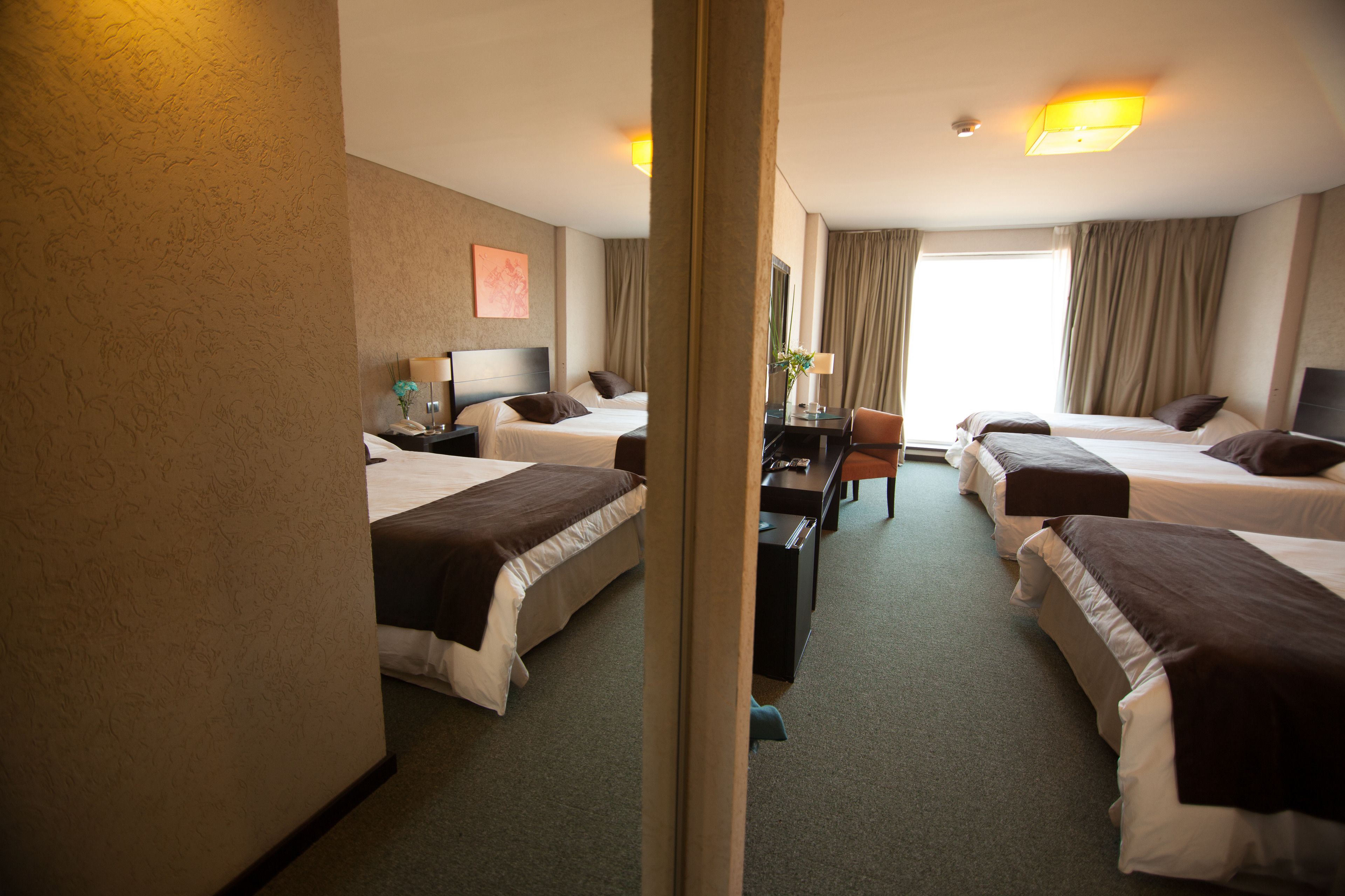 A hotel room with two beds, a desk, and a chair.
