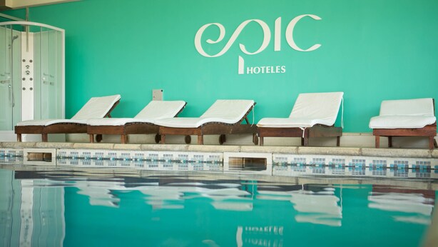 A swimming pool with lounge chairs and a wall with the text "Epic Hotels". - Epic Hotel San Luis (La Punta)