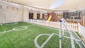 A children's play area with a soccer field, climbing structures, and a trampoline. - Qasr Al Sarab Desert Resort by Anantara (Al Mirayr)