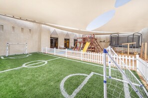 A children's play area with a soccer field, climbing structures, and a trampoline. - Qasr Al Sarab Desert Resort by Anantara (Al Mirayr)