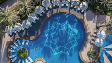 Relax by the pool surrounded by lush greenery and lounge under the shade of umbrellas.