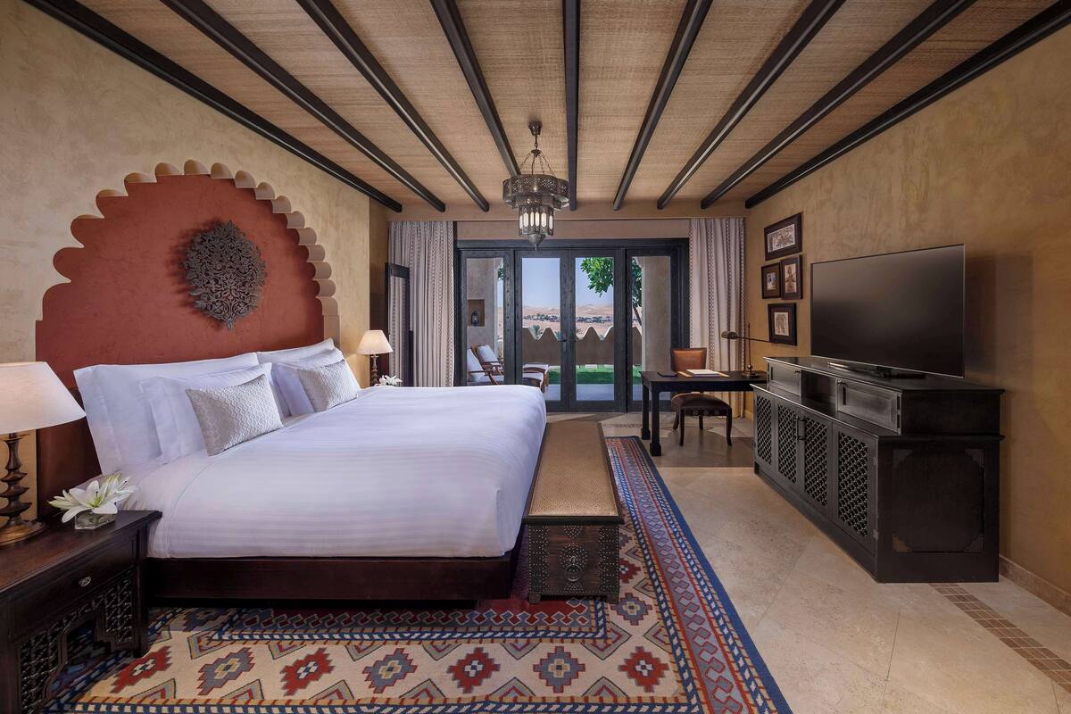 A spacious bedroom with a large bed, a television, and a view of the outdoors.