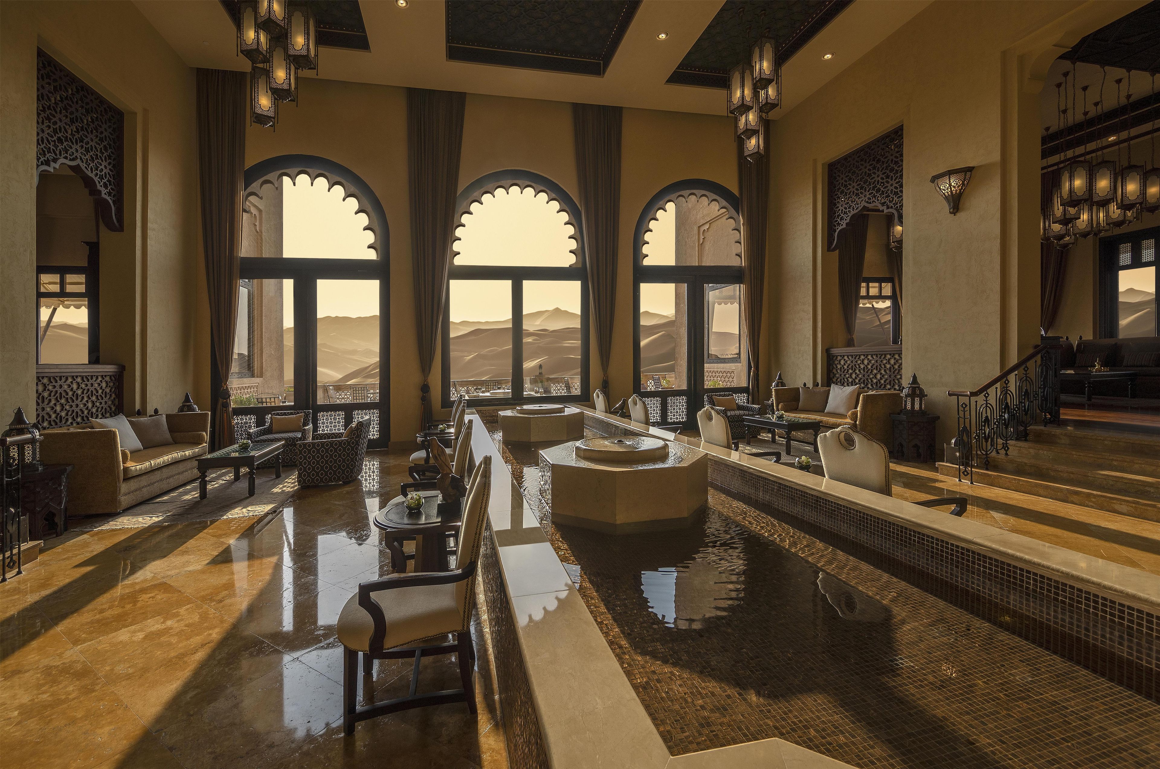 A luxurious indoor pool area with seating arrangements and a view of the desert landscape.